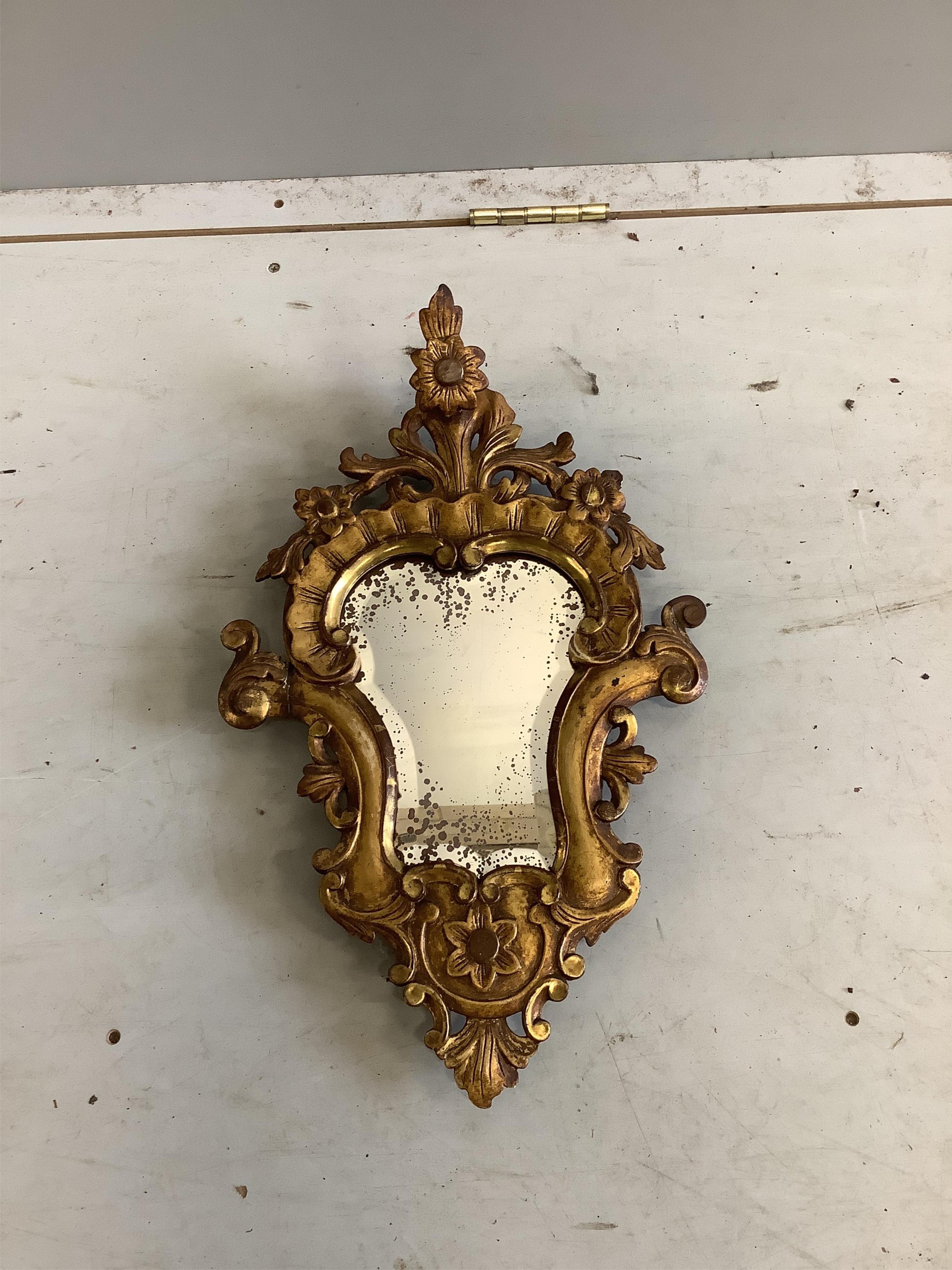 A pair of cartouche shaped carved giltwood wall mirrors, width 31cm, height 51cm. Condition - poor to fair